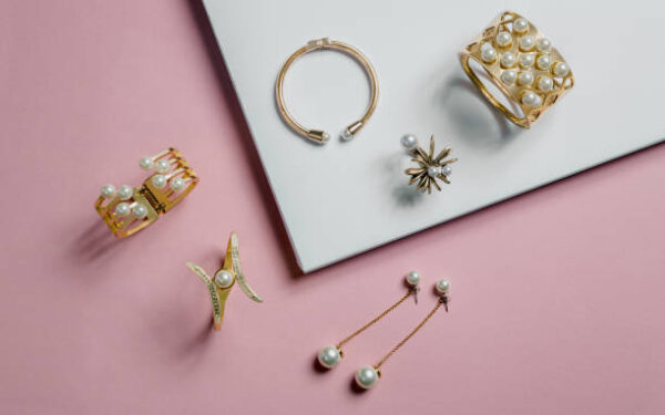 Golden bracelets and earrings on pink and white background