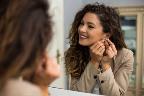 Businesswoman is putting earrings while preparing for work.