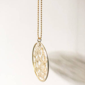 Gold round necklace with butterflies illuminated by the sun